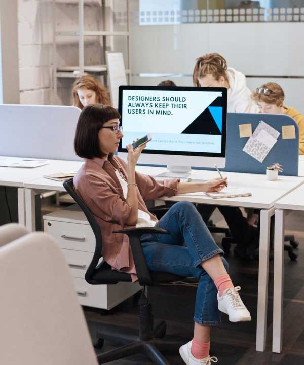 A woman sitting at a desk, focused on her computer screen, working diligently.